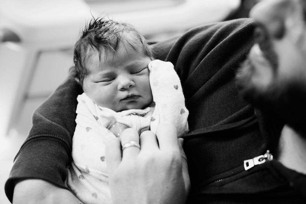 dad cradling newborn black and white portrait