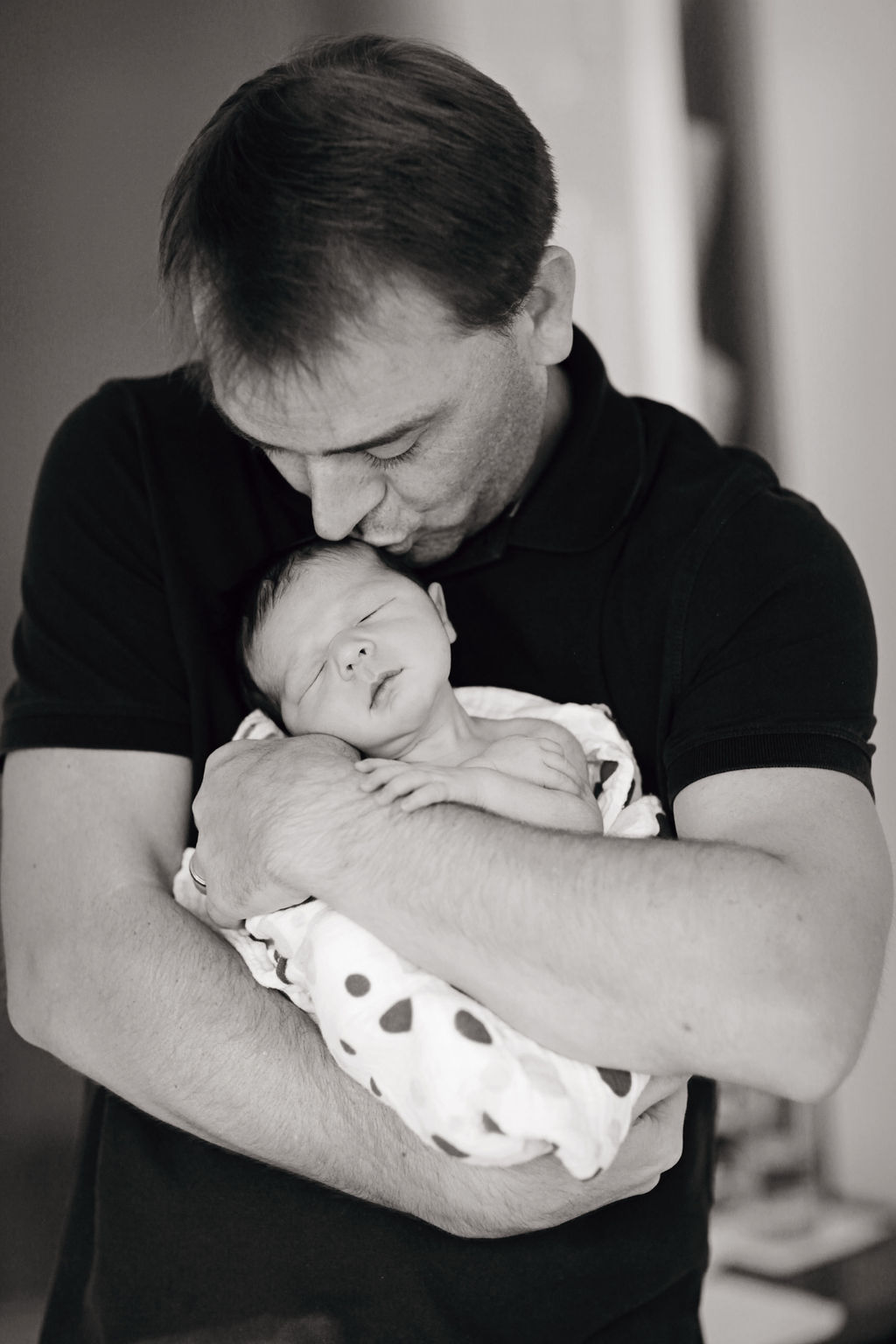 dad kissing newborn black and white portrait