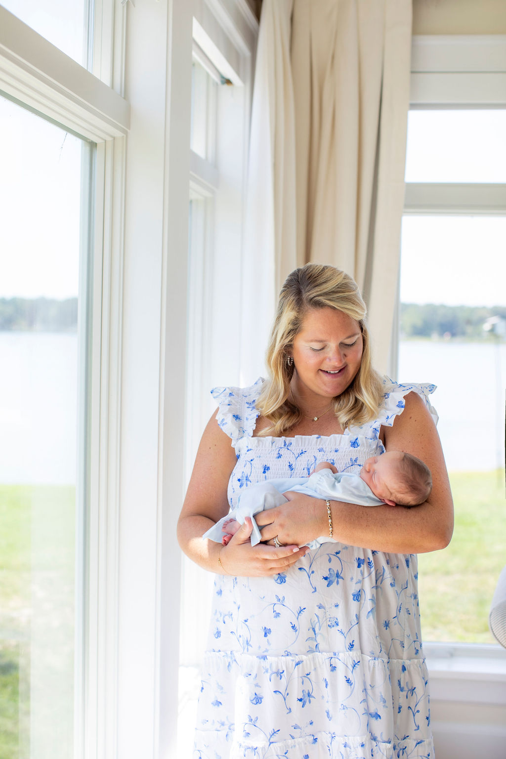 mom cradling newborn window portrait