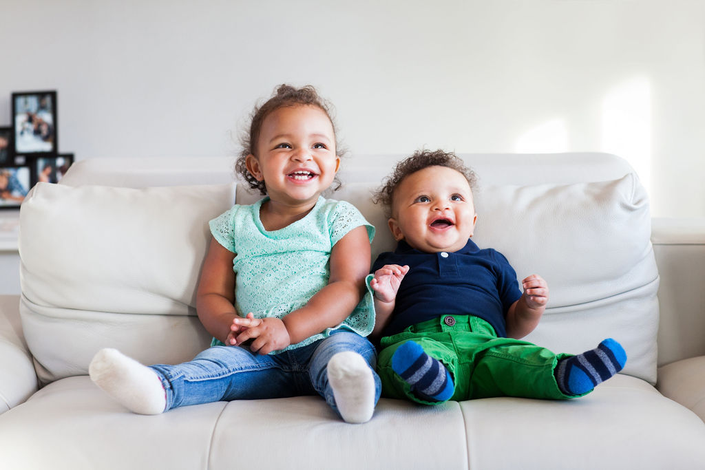 toddlers laughing on sofa portrait